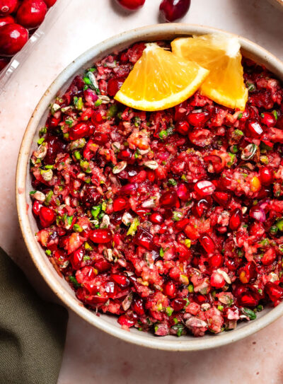 Bowl of cranberry relish with decorative orange wedges.
