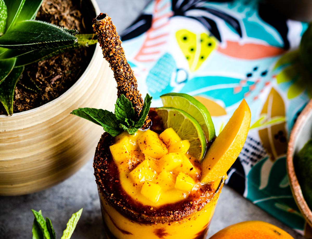 Chopped mango on top of smoothie with homemade tamarind straw.